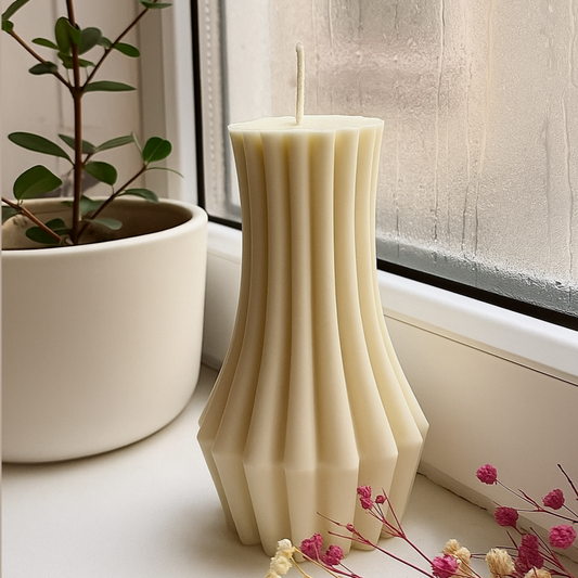 White textured candle on a windowsill with a plant and flowers in the background